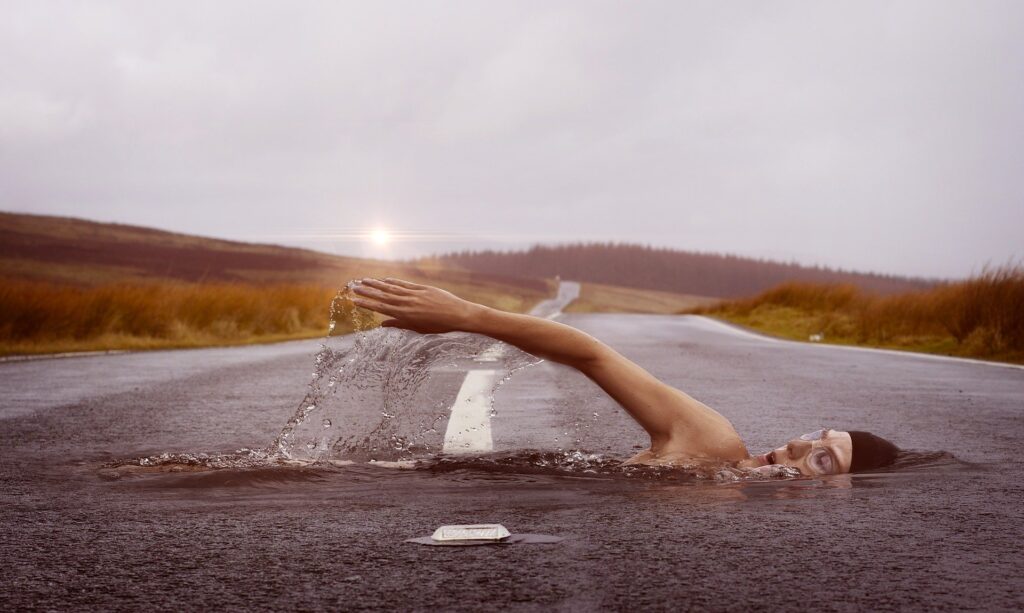 Alternate reality of woman swimming in a road. 